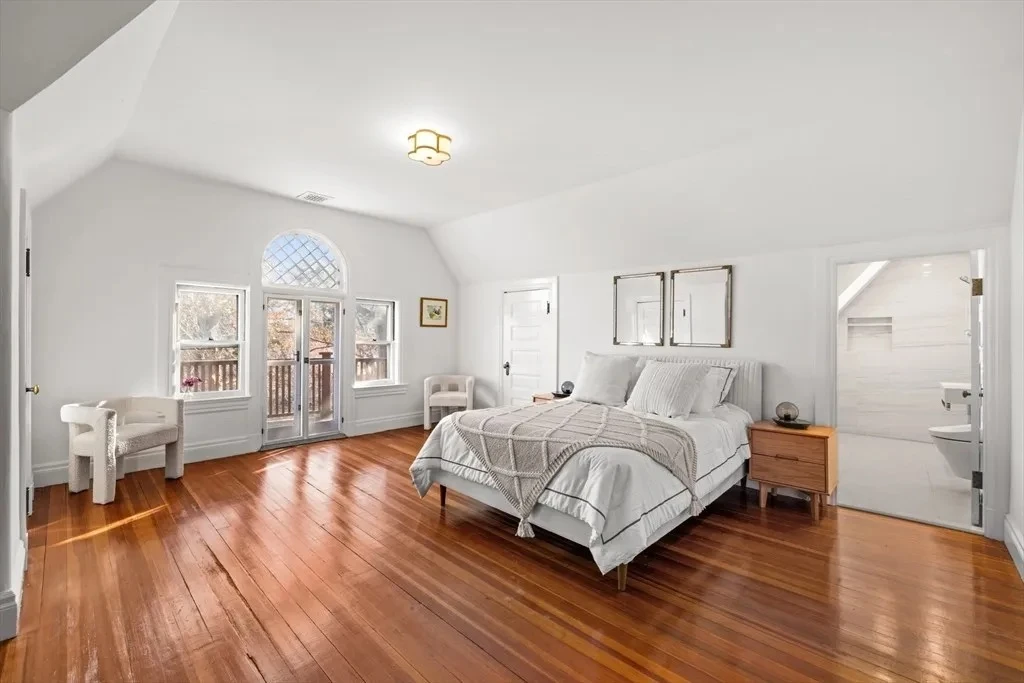 Bright Northampton primary bedroom with a king-size bed, wood flooring, and a vaulted ceiling